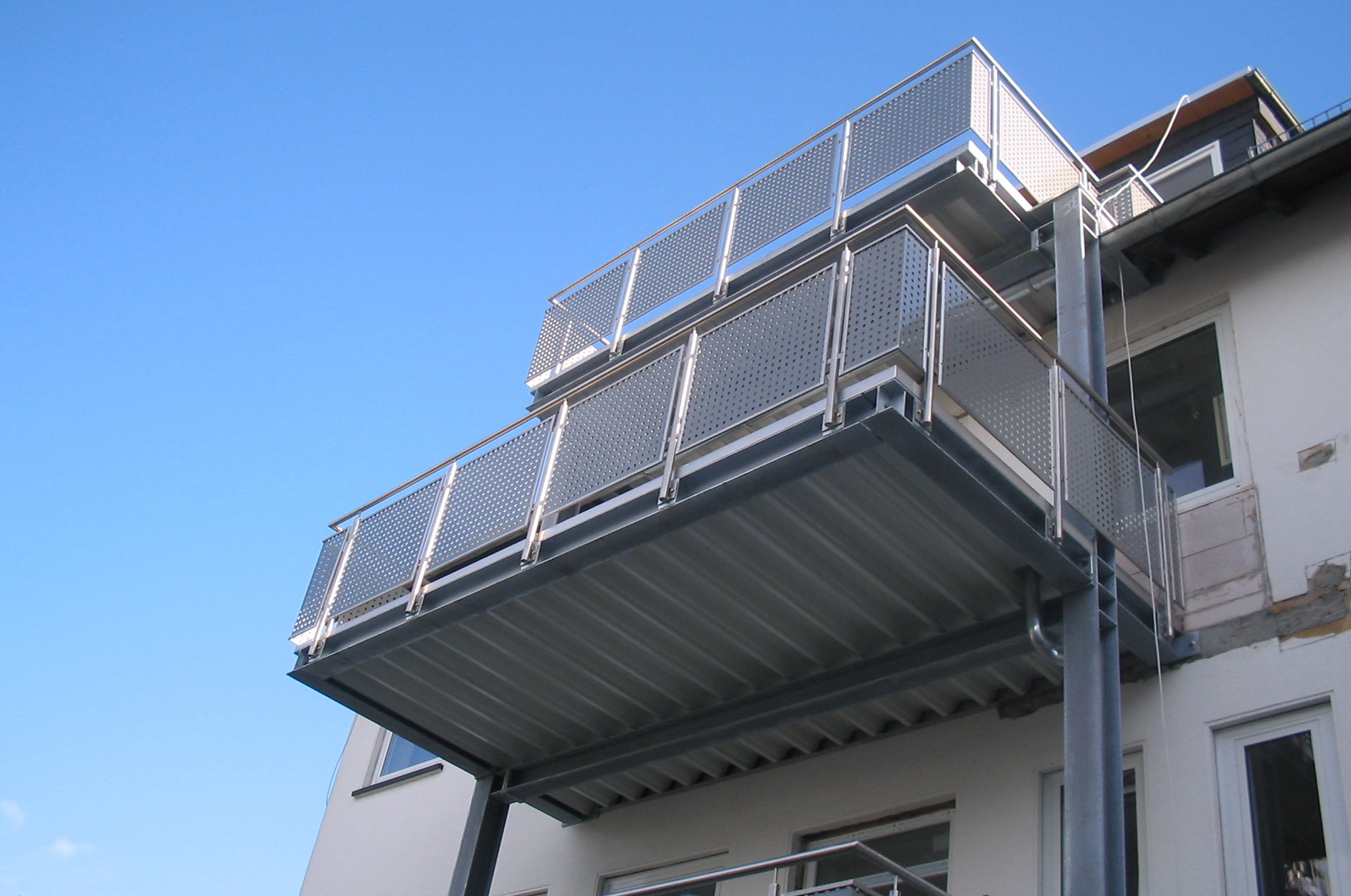 Ein Balkon an der Seite eines Gebäudes mit einem blauen Himmel im Hintergrund.