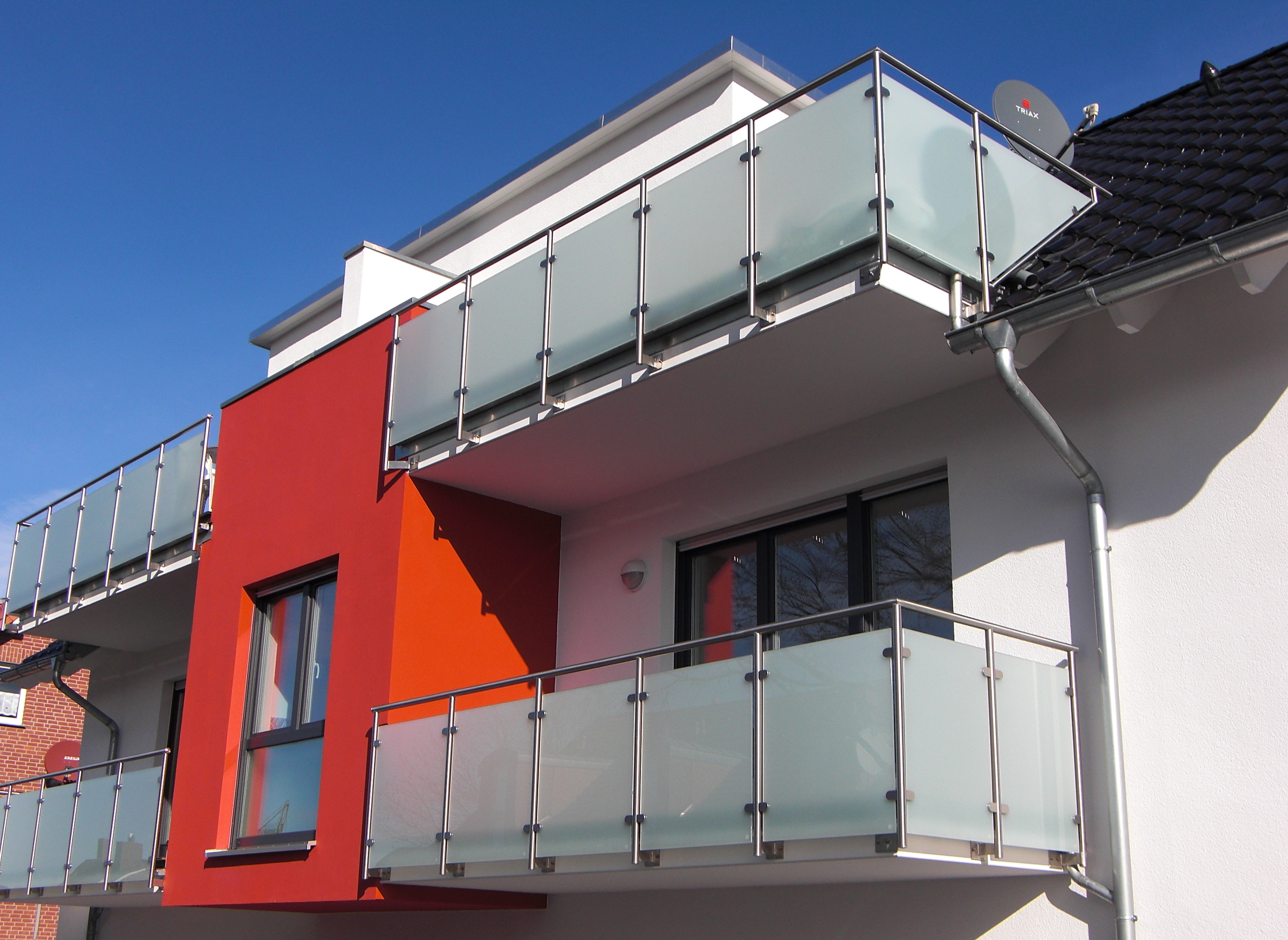 Ein Gebäude mit einem Balkon und einer Satellitenschüssel auf dem Dach.