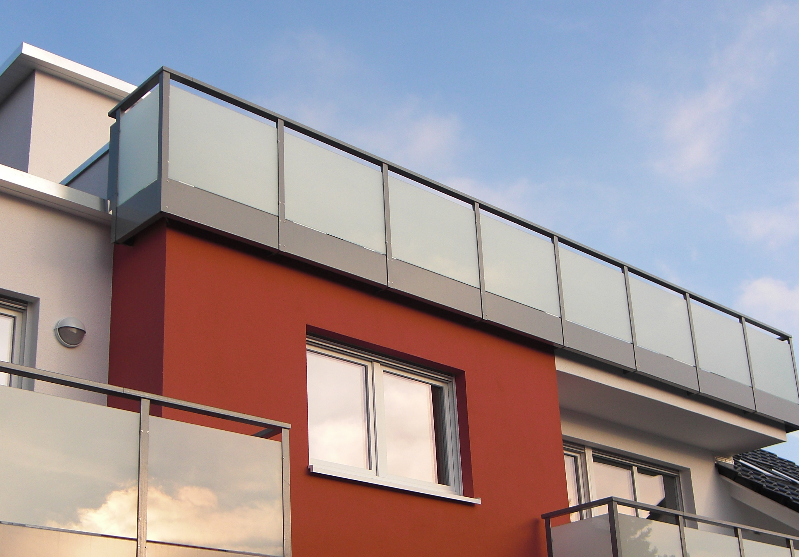 Ein Balkongeländer aus Edelstahl mit Milchglasscheiben.