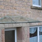 Glasvordach an einer Haustür mit Edelstahlhalterung